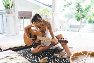 Woman playing acoustic guitar on terrace of hotel