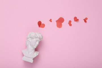 David bust with hearts on pink background. Creative love layout. Concept pop. Minimal still life. Flat lay. Top view