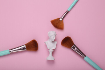 Venus Bust with makeup brushes on pink background. Minimal beauty still life. Flat lay
