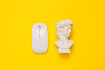 Minimal still life. Antique David bust with pc mouse on yellow background