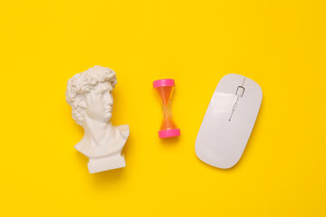 Minimal still life. Antique David bust with hourglass and pc mouse on yellow background