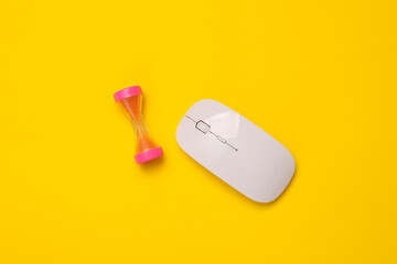Pc mouse with hourglass on yellow background. Top view