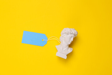 David Bust with tag on yellow background. Minimal still life. Flat lay