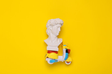 David bust with scooter on yellow background. Minimal still life