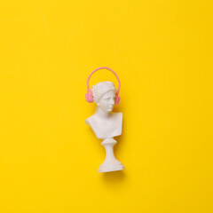 Venus bust with headphones on yellow background. Minimal still life. Flat lay