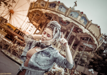 Extraordinary emotional cheerful woman with African braids and bright makeup spends time in amusement park. Lifestyle