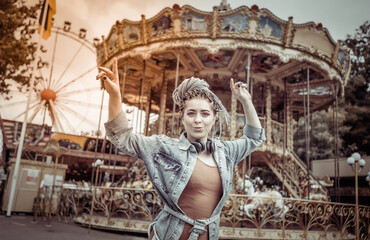 Extraordinary emotional cheerful woman with African braids and bright makeup spends time in amusement park. Lifestyle