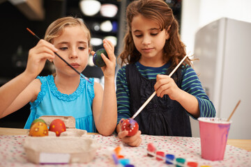 Theyre into their arts and crafts. Shot of two little girls painting easter eggs.