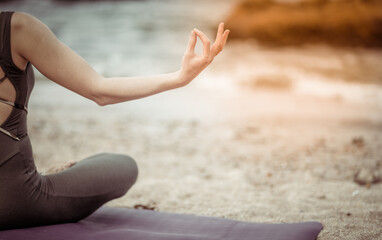 Young woman in sportswear in lotus position on the beach. Harmony