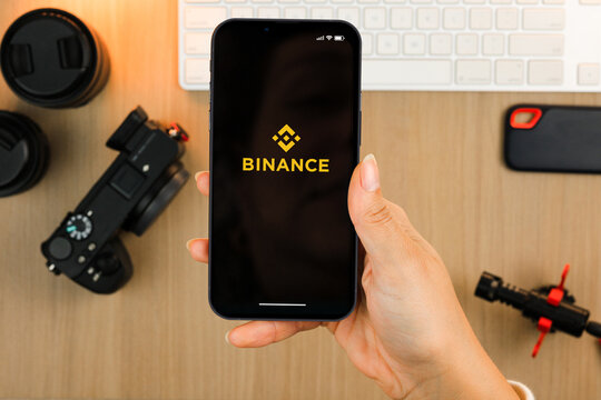 Female hand holding a smartphone iPhone 13 with Binance cryptocurrency exchange app on the screen. Content creator environment with keyboard, camera and mic. Rio de Janeiro, RJ, Brazil. March 2022