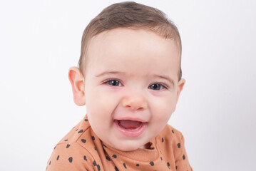 Close up portrait of an adorable sweet baby sitting over white studio background wearing animal print sweater and smiling to the camera. Childhood, innocence and happiness concept. 