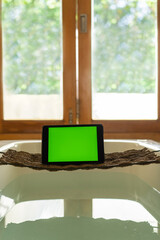 Tablet on a stand in the bathroom against the background of the window. Chroma key screen, mockup