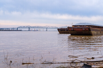 Two barges docked on the Mississippi River with the Huey P. Long Bridge in the background on March...