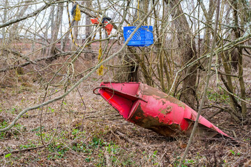 Red buoy stuck in sediment and other discarded items amidst vegetation in sediment along the...