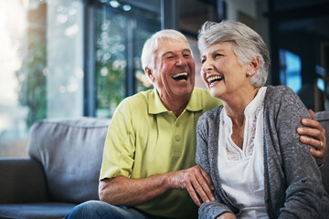 When youre laughing, youre living. Shot of a happy senior couple relaxing together on the sofa at...