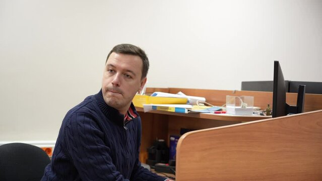 Cunning employee is engaged in illegal business at workplace and constantly looks around at colleagues so that he is not caught playing computer games during working hours or watching obscene videos