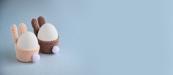 Easter holiday preparation. Crocheted egg basket in the shape of Easter bunny with a tail. Egg stand in the form of a bunny. White eggs. Postcard. DIY crafts with children with your own hand. Banner