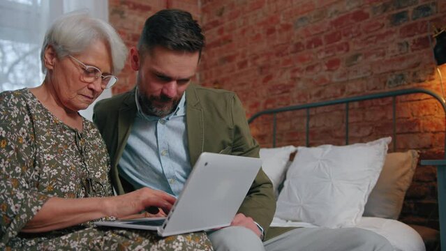 middle-aged caucasian man helping his grandmother with the usage of computer. High quality 4k footage