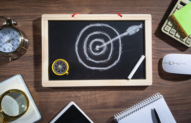 Target and arrow on small chalkboard with a business objects. Goals. Success