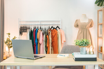 Online clothing store with laptop, notebook, clothing rack, mannequin and object decoration on desk in home office