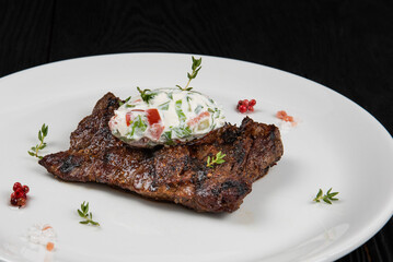 Grilled juicy marinated beef hanger steak on a plate with cream and vegetable