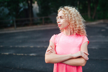 A young curly blonde of athletic build performs a warm-up before training at the stadium. Outdoor...