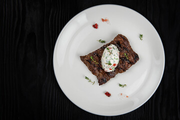 Grilled juicy marinated beef flank steak on a plate with cream and vegetable
