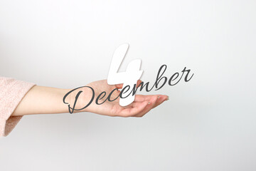 December 4th. Day 4 of month, Calendar date. Calendar Date floating over female hand on grey background. Winter month, day of the year concept.