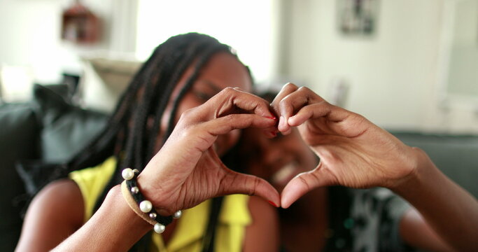 Mother and daughter making heart symbol with hands. Black African ethnicity
