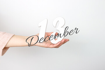 December 13rd. Day 13 of month, Calendar date. Calendar Date floating over female hand on grey background. Winter month, day of the year concept.