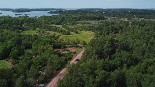 Car driving in Brando Island in the middle of woods in Aland Islands, Finland, aerial following shot