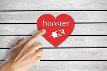 A hand holding red heart paper shape with booster word and syringe icon for vaccinated or...