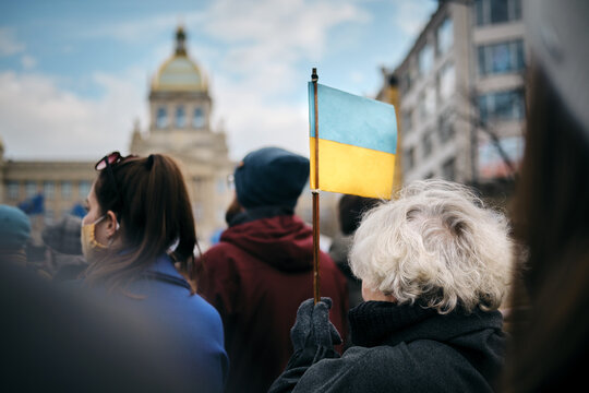 photos from the demonstration showing a woman holding a Ukrainian flag in support of Ukraine