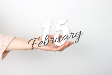 February 15th. Day 15 of month, Calendar date. Calendar Date floating over female hand on grey background. Winter month, day of the year concept.