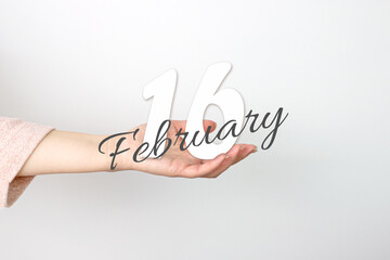 February 16th. Day 16 of month, Calendar date. Calendar Date floating over female hand on grey background. Winter month, day of the year concept.