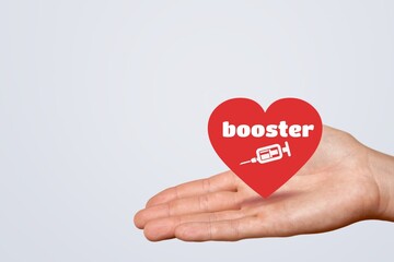 Fototapeta premium A hand holding red heart paper shape with booster word and syringe icon for vaccinated or inoculation