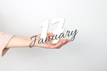 January 17th. Day 17 of month, Calendar date. Calendar Date floating over female hand on grey background. Winter month, day of the year concept.