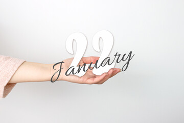 January 22nd. Day 22 of month, Calendar date. Calendar Date floating over female hand on grey background. Winter month, day of the year concept.