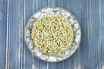 Dry noodles in a plate on a wooden table.