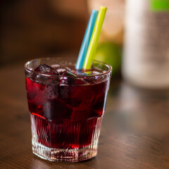 cherry alcohol drink with color straw on wooden table cube