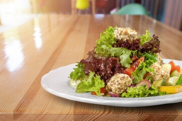 Healthy salad bowl with different lettuce, chicken, cheese on the table in restaurant.