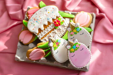 background banner greeting card for Happy Easter with colorful eggs gingerbread cookies in shape of unicorns in egg box on pink silk fabric background