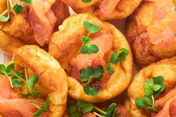 Yorkshire pudding. Traditional English Yorkshire pudding with salmon and radish microgreens side dish on white plate and light grey background table. Top view.