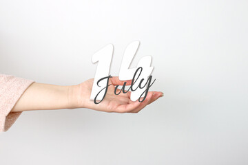 July 14th. Day 14 of month, Calendar date. Calendar Date floating over female hand on grey background. Summer month, day of the year concept.