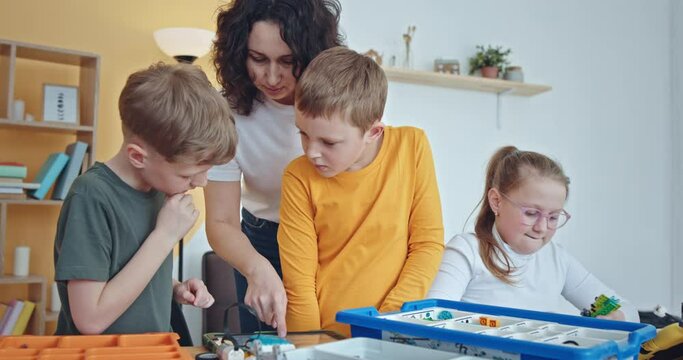 Mother and children play with Bricks sitting at table in room