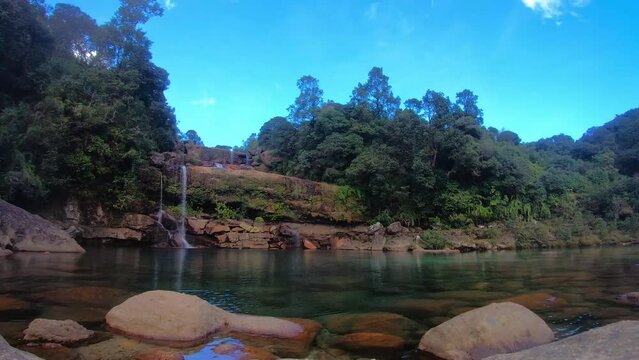 natural waterfall falling from mountain top with dramatic blue sky at forests time lapse