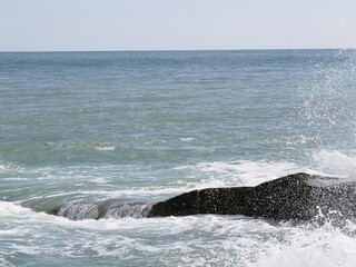 Fototapeta premium waves splashing and water spray over the rocks in the sea