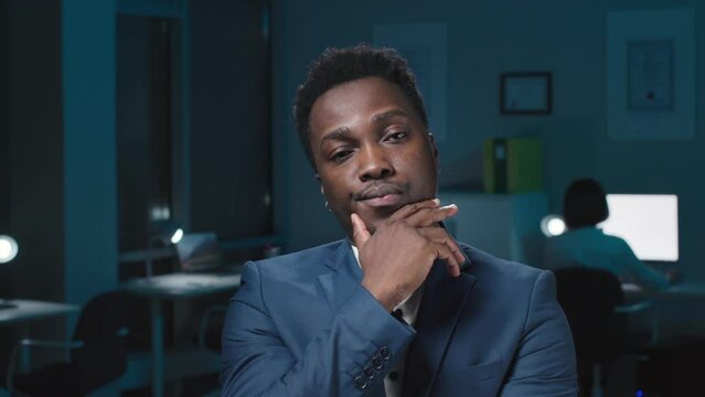Portrait of pensive African-American businessman look at camera and nod
