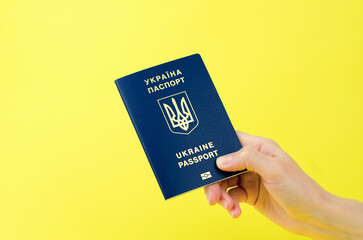 Ukrainian passport in a female hand on a yellow background