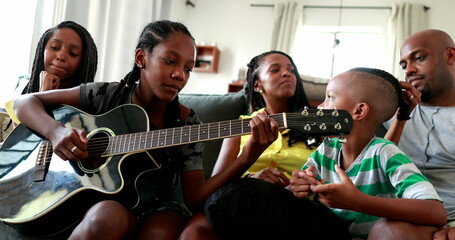 Casual black African family bonding thogether through music guitar. Daughter playing musical instrument